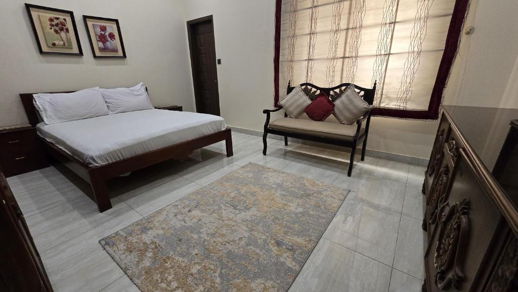 Un dormitorio con una cama y una silla y una ventana. en Two bedroom furnished apartment in Main Shahrah e Faisal Karachi, en Karachi
