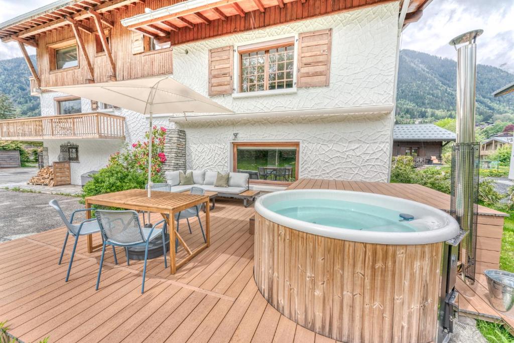 un bain à remous sur une terrasse en face d'une maison dans l'établissement Appartement de Luxe avec Jacuzzi, Vue Montagne et Jardin, à Chamonix-Mont-Blanc