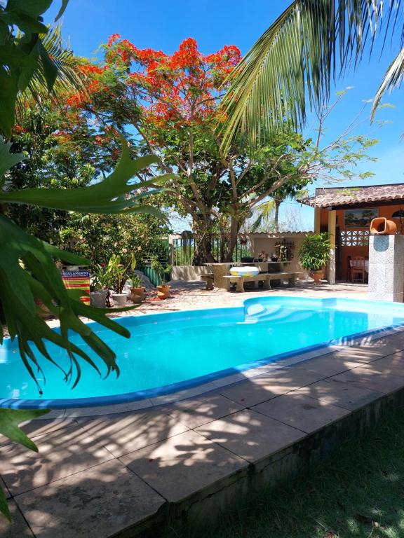 a swimming pool in front of a house with trees at Paraíso nas férias in Porto Seguro