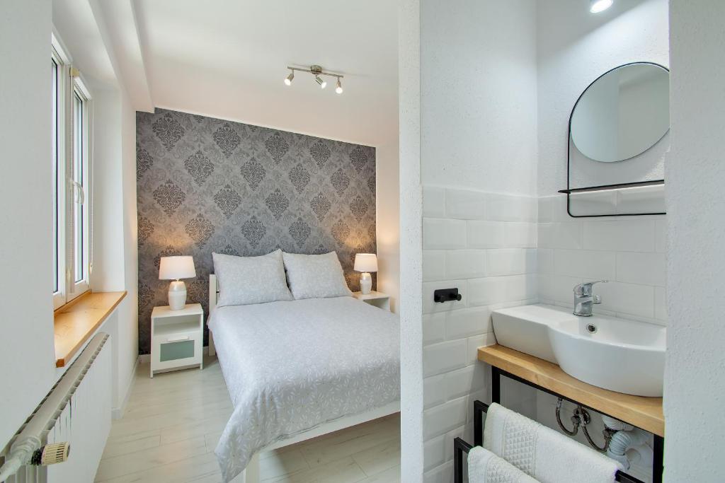 a bedroom with a bed and a sink and a mirror at Leokadia przy plaży kwatery prywatne in Mielno