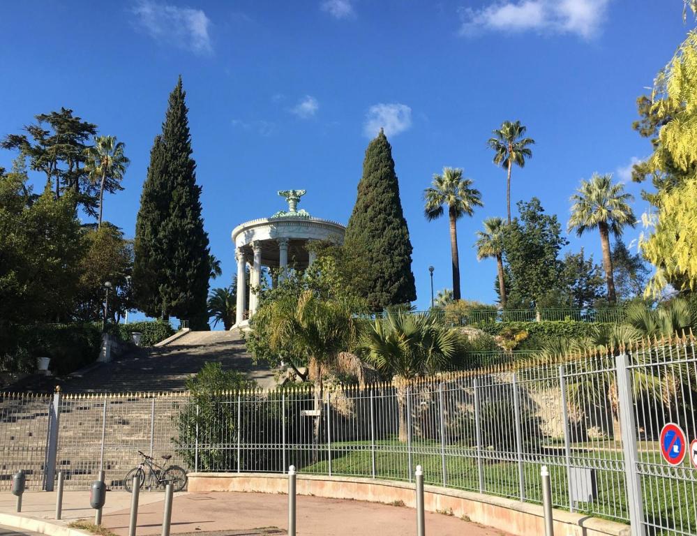 un monument dans un parc avec des palmiers et une clôture dans l'établissement Joli appartement Parc Chambrun, à Nice