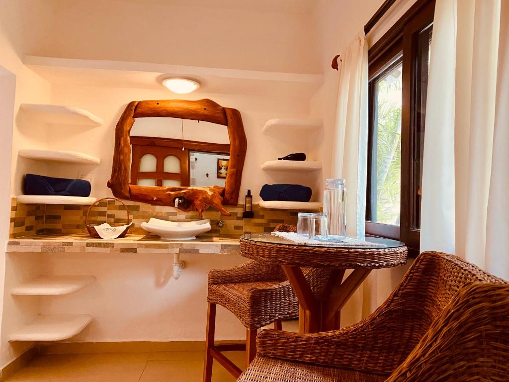 a bathroom with a vanity with a mirror and wicker chairs at Hotel Para Ti - Adults Only in Holbox Island