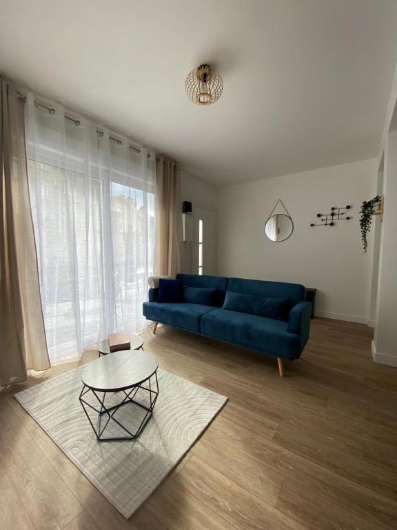 Una sala de estar con un sofá azul y una mesa. en Les Gites de Saint Thierry, en Reims
