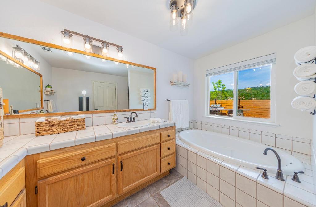 un bagno con vasca e un grande specchio di Hidden Falls Retreat Peaceful Guesthouse Near Yosemite a Oakhurst