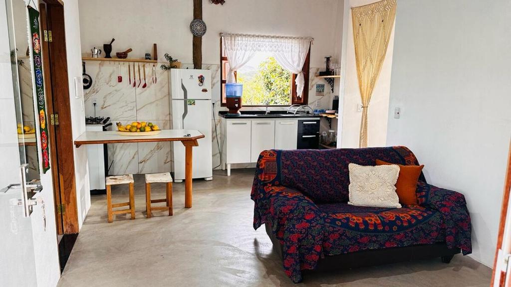 a living room with a couch and a table in a kitchen at Refúgio do Boto, casa nova em meio a natureza rústica in Alto Paraíso de Goiás