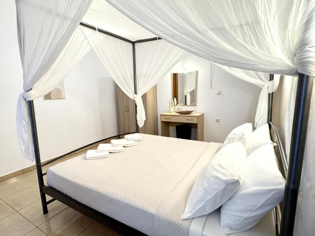a bedroom with a white canopy bed with white pillows at Pachia Ammos Falasarna in Falasarna