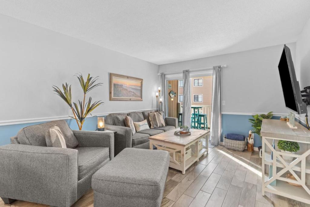 a living room with a couch and a tv at Cast a Waves. Condo with partial Atlantic views and a POOL in Carolina Beach