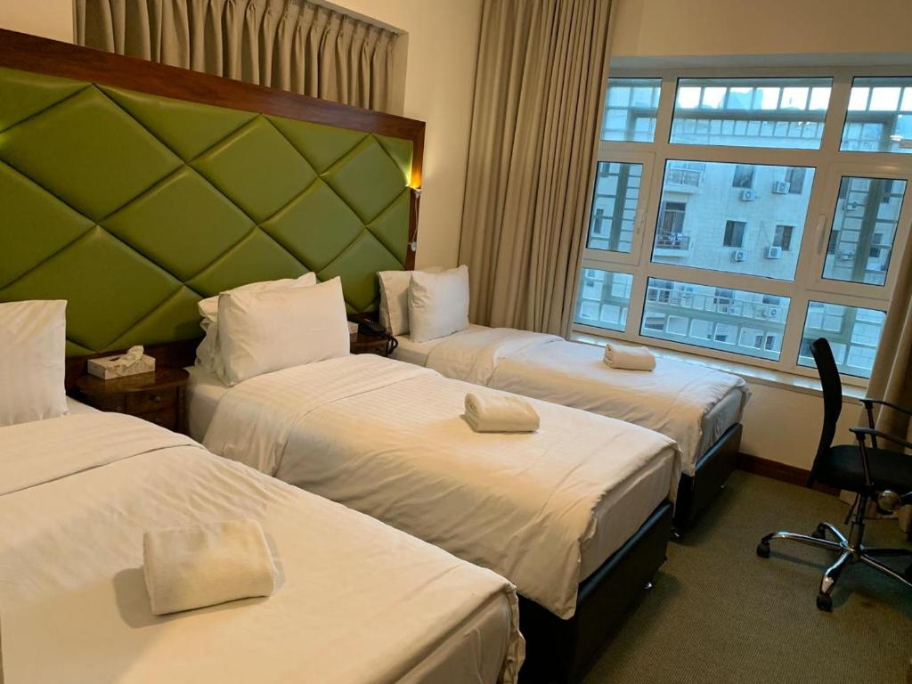 a hotel room with two beds and a window at Holyland Hotel Amman in Amman