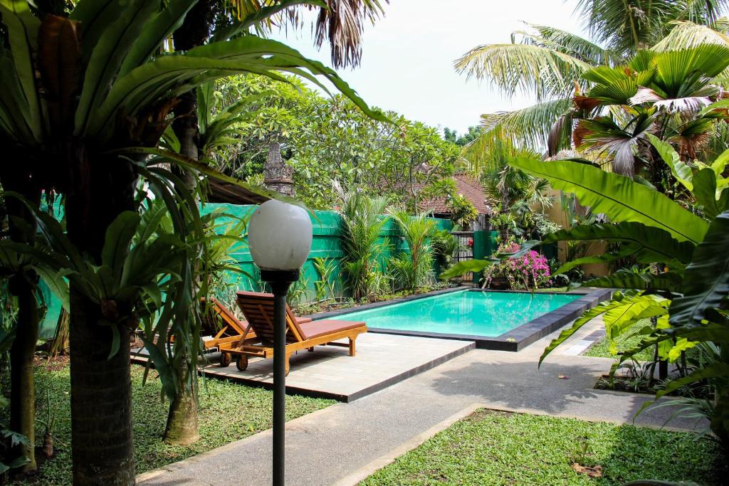 einen Pool in einem Garten mit einer Bank und einer Lampe in der Unterkunft Secret Garden Sky in Ubud