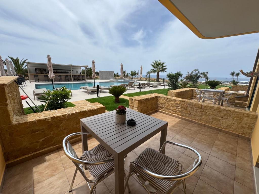 a table and chairs on a patio with a pool at Pachia Ammos Falasarna in Falasarna