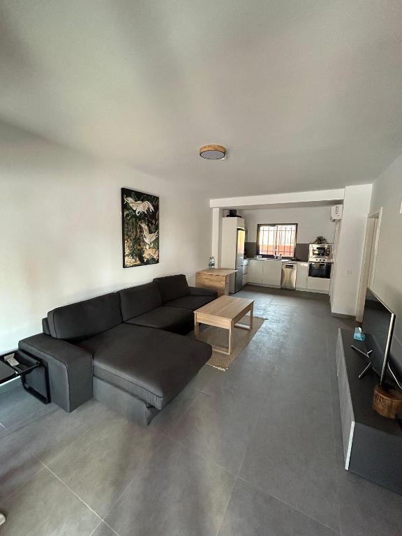 a living room with a black couch and a table at Bungalow - Playa Meloneras in San Bartolomé