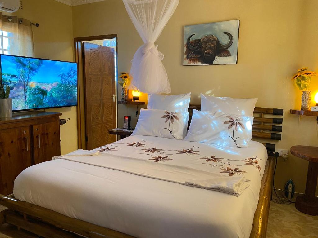 a bedroom with a large white bed with flowers on it at Bush Adventure Guest House in Kasane