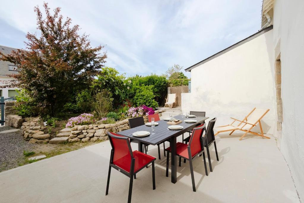 Une table à manger et des chaises sont disponibles sur la terrasse. dans l'établissement Entre Terre & Sel Maison de Charme Marais Salants, à Guérande