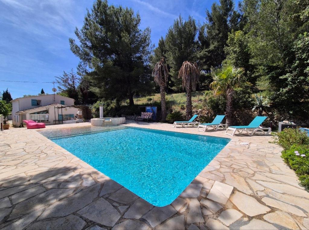- une piscine dans une cour avec 2 chaises bleues dans l'établissement La Bergerie, maison T3 avec Piscine, à Sanary-sur-Mer