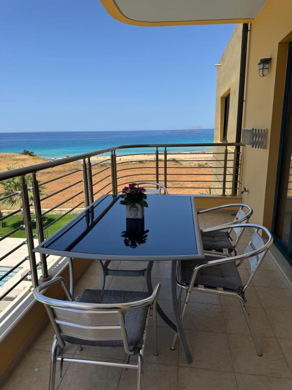 a table and chairs on a balcony with the beach at Pachia Ammos Falasarna in Falasarna