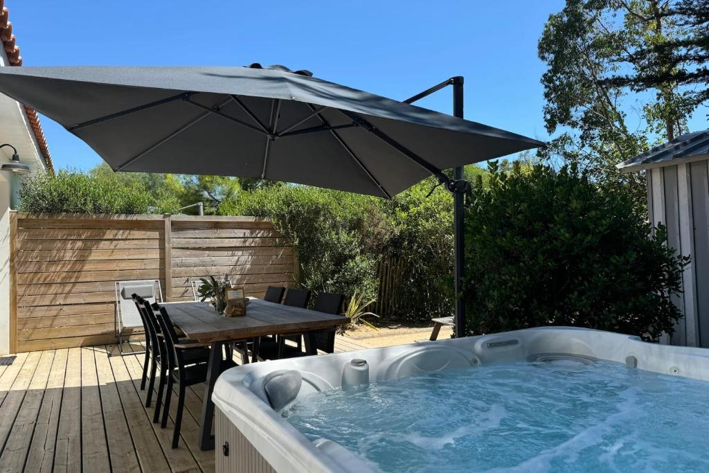 a hot tub with a table and an umbrella at Villa Thaïlande - Domaine Le Sherwood in Notre-Dame-de-Monts