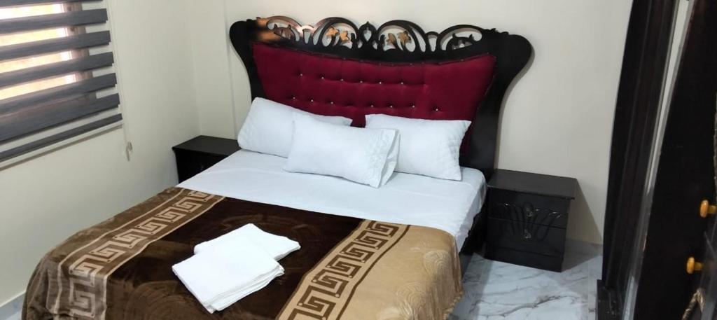 a bedroom with a bed with a red headboard at Petra bed house in Petra