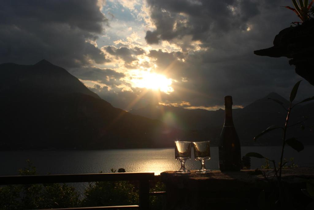 a bottle of wine and glasses on a table with the sunset at Rosa House Varenna in Varenna