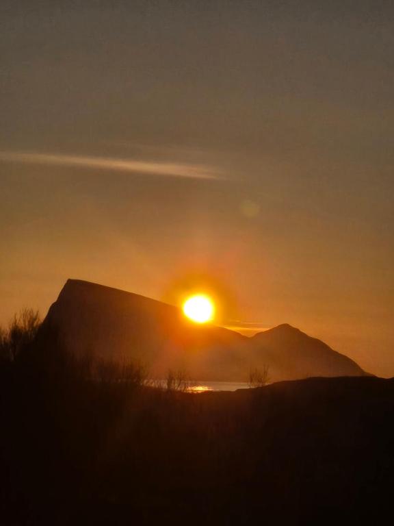 a sunset over a mountain with the sun setting at Cabin Aurora Borealis in Sommarøy
