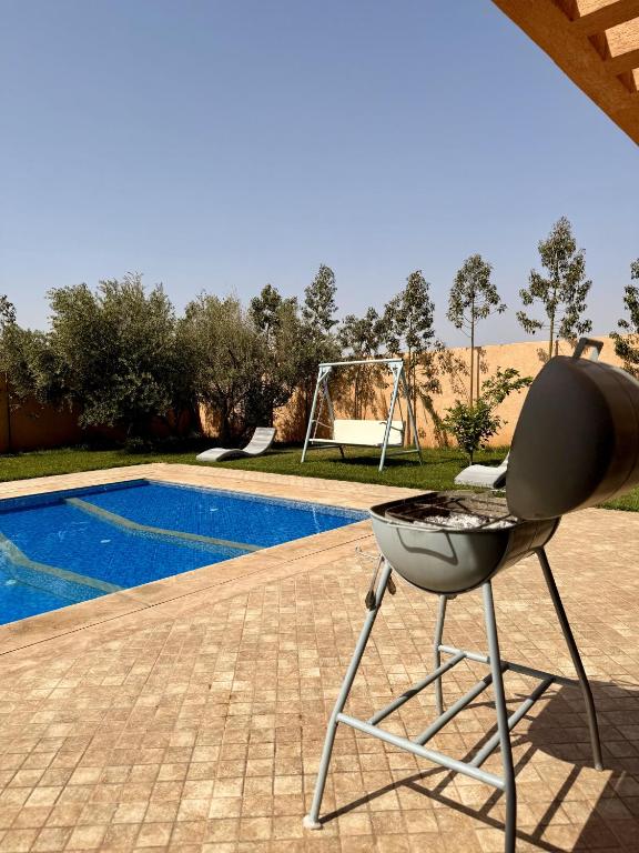 a barbecue grill sitting on a patio next to a pool at The Atlas View and Elegant Villa Marrakech in Marrakech