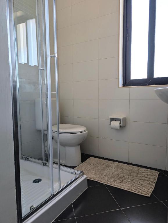 a bathroom with a toilet and a glass shower at Sunset Haven Manikata - Walking distance to Golden Bay in Manikata