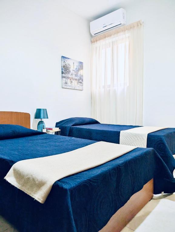 a room with two beds with blue sheets at Sunset Haven Manikata - Walking distance to Golden Bay in Manikata