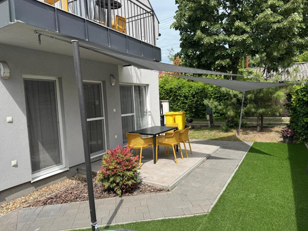 patio ze stołem, krzesłami i parasolem w obiekcie Silver Lelle Apartman Balatonlelle w mieście Balatonlelle
