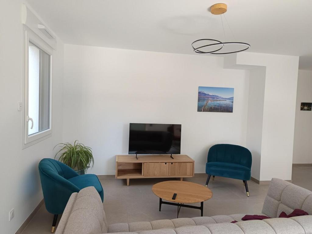un salon avec un canapé, des chaises et une télévision dans l'établissement Annecity, à Annecy
