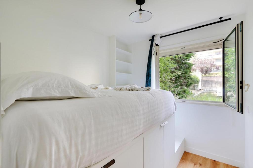 a bed in a white room with a window at Au pied de l'arche in Courbevoie