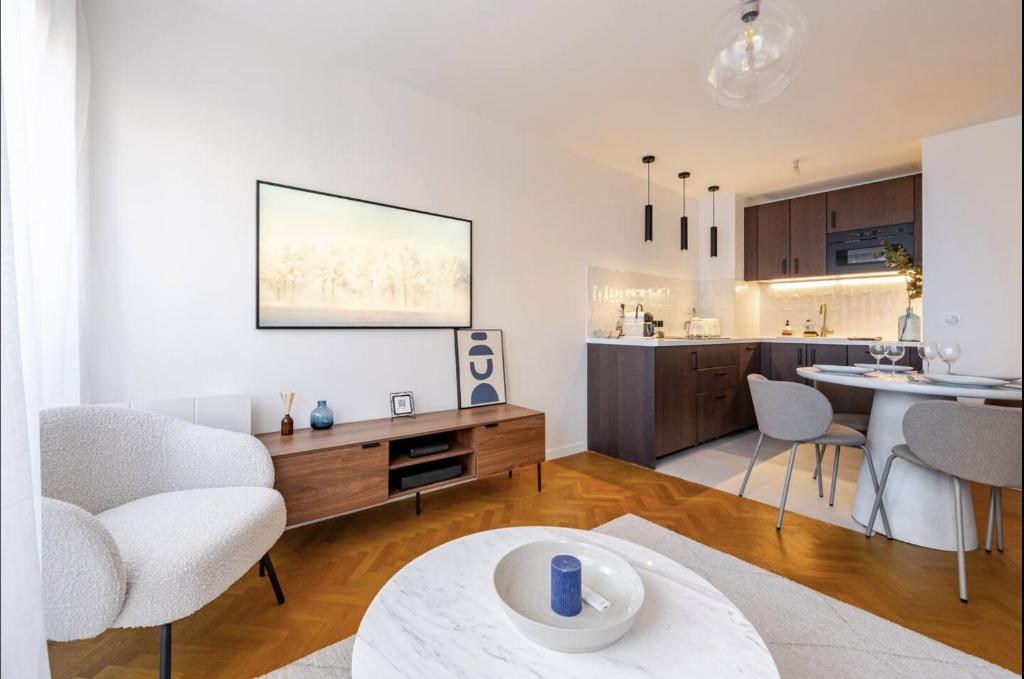 Il comprend un salon et une cuisine avec une table et des chaises. dans l'établissement Charmant appartement proche Disney avec Parking, à Montévrain