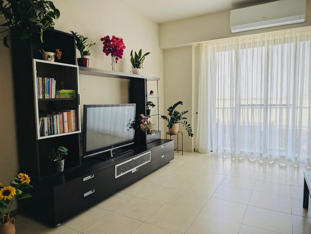 a living room with a tv and a book shelf at Sunset Haven Manikata - Walking distance to Golden Bay in Manikata