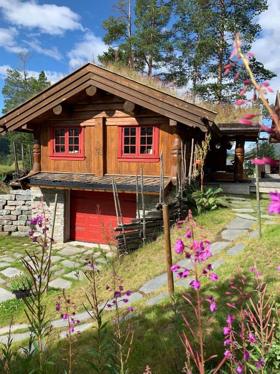 a log cabin with a red door and some flowers at Holiday cabin, Kristianplass at Bjorli, Lesja in Bjorli
