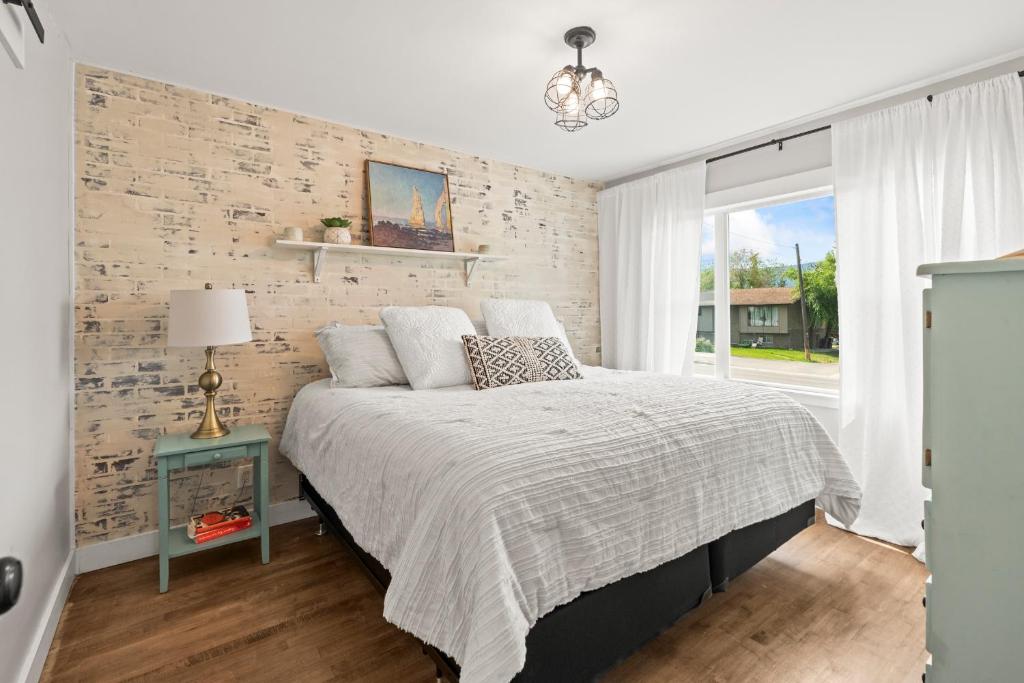 a bedroom with a bed and a brick wall at Stunning Heritage Home, Sleep 10, Hot Tub, Private Yard, Firepit, in Vernon