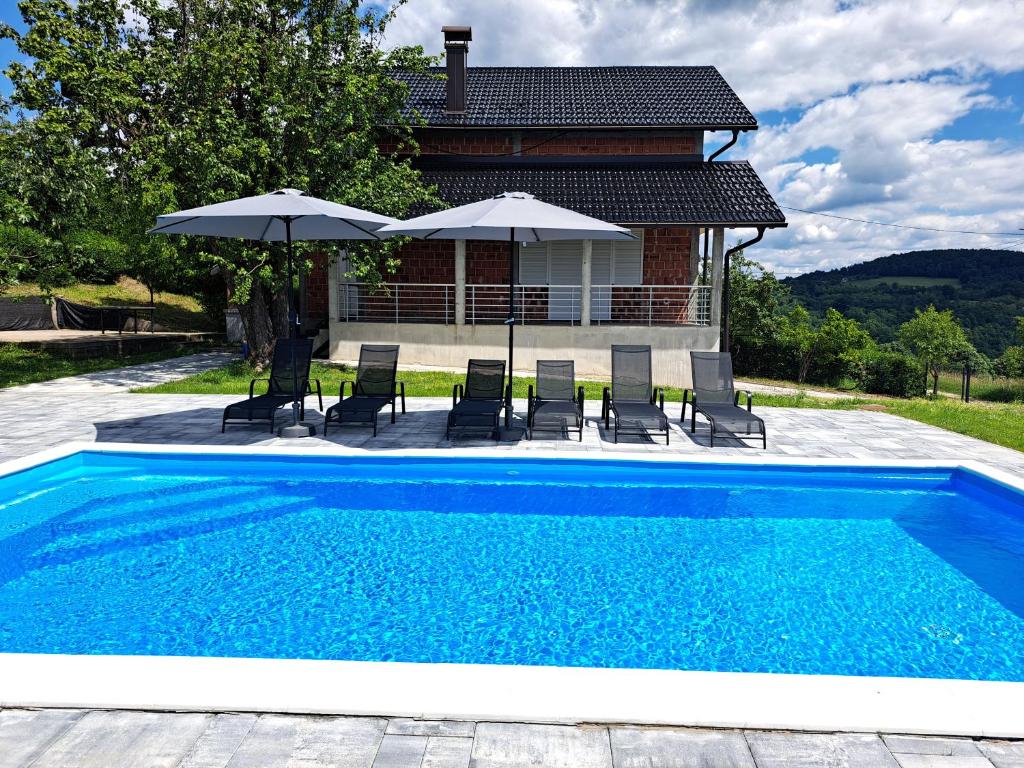 una piscina con sillas y sombrillas frente a una casa en Villa Sunset, en Banja Luka