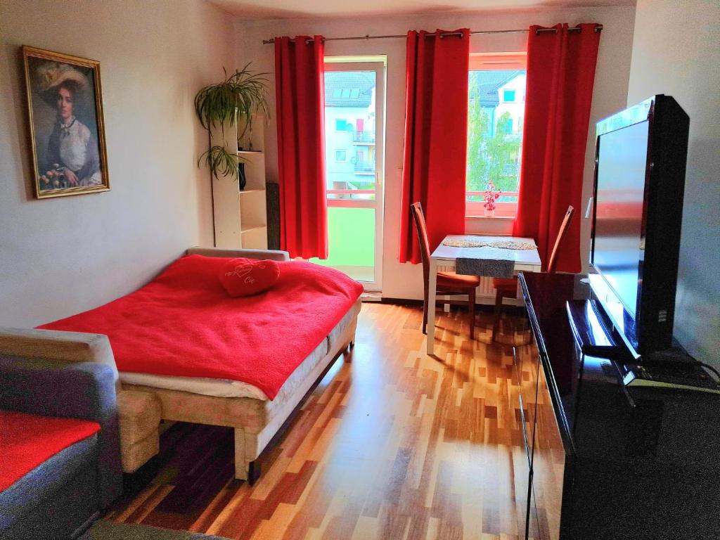 Una sala de estar con cortinas rojas y un televisor. en Stronska, en Wroclaw