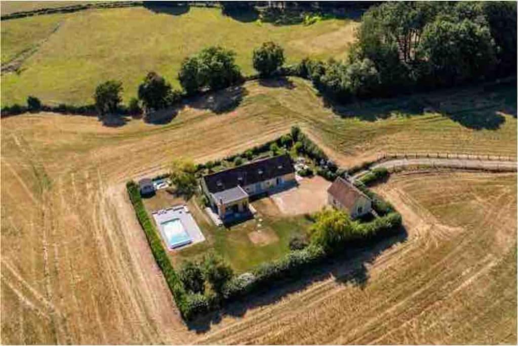une vue aérienne d'une maison dans un champ dans l'établissement Magnifique longère du Perche avec vue panoramique et piscine pour 9 personnes, à Le Gué-de-la-Chaîne