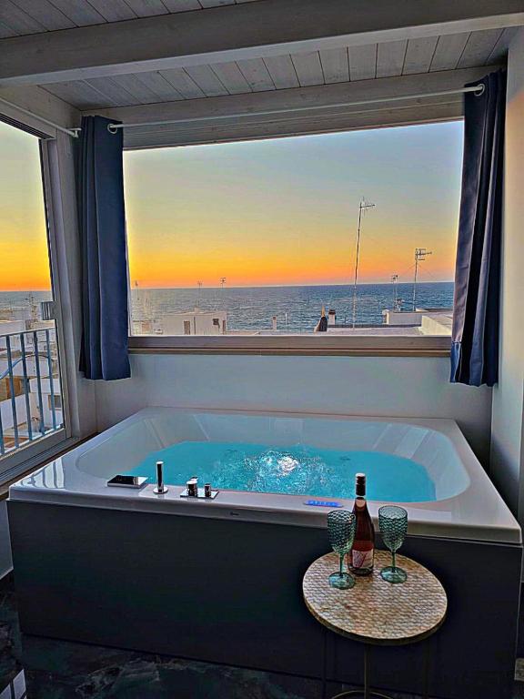 滨海波利尼亚诺Mareggia的浴缸配有一瓶葡萄酒和两杯酒