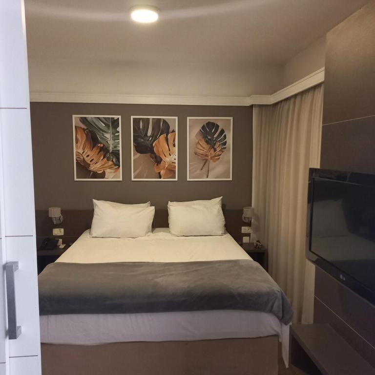 a bedroom with a bed with four pictures on the wall at 154apartamento lindo no itaim bibi in Sao Paulo