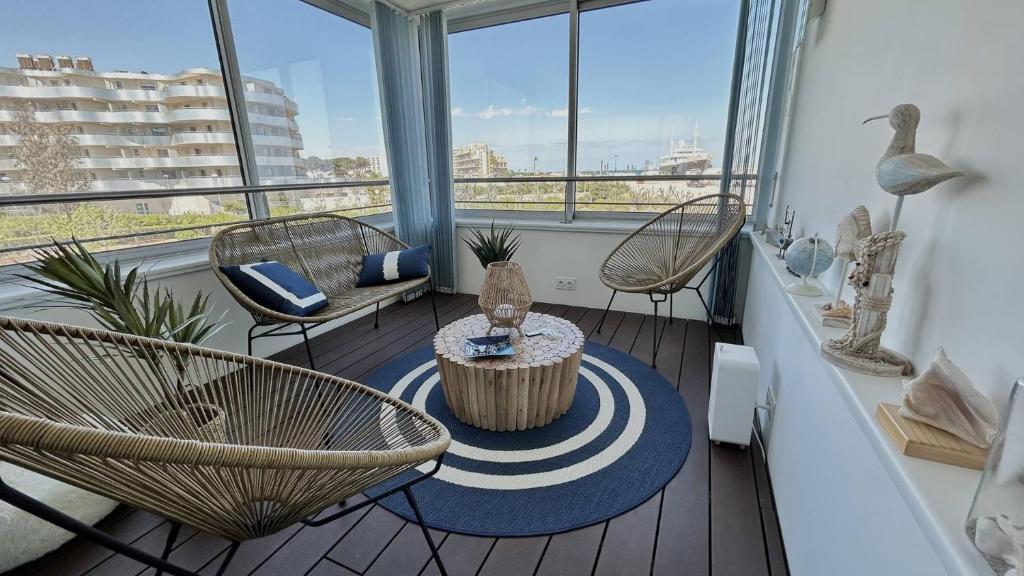 un salon avec des chaises, une table et des fenêtres dans l'établissement Appartement avec vue imprenable sur la mer et le lydia 5EST106, au Barcarès
