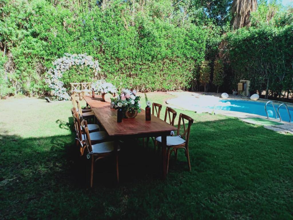 a wooden table with chairs in the yard with a pool at كومباوند ستيلا بجوار مدينتي in Cairo