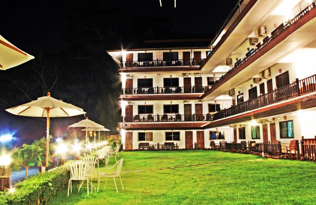 un hôtel avec des tables et des parasols dans une cour dans l'établissement Namkhong Riverside, à Chiang Khong