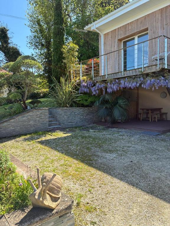 une maison avec un jardin et un balcon avec des fleurs violettes dans l'établissement Appartement Rez de chaussée, au Le Verdon-sur-Mer
