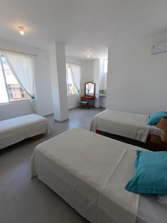 a hotel room with two beds and a chair at Gallardos Suite in Puerto Ayora
