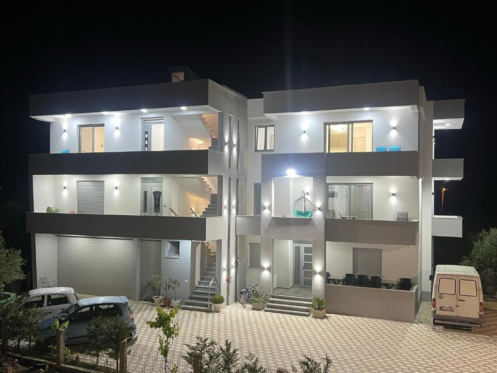 a large white building with a car parked in front of it at Apartments Bojku in Ulcinj