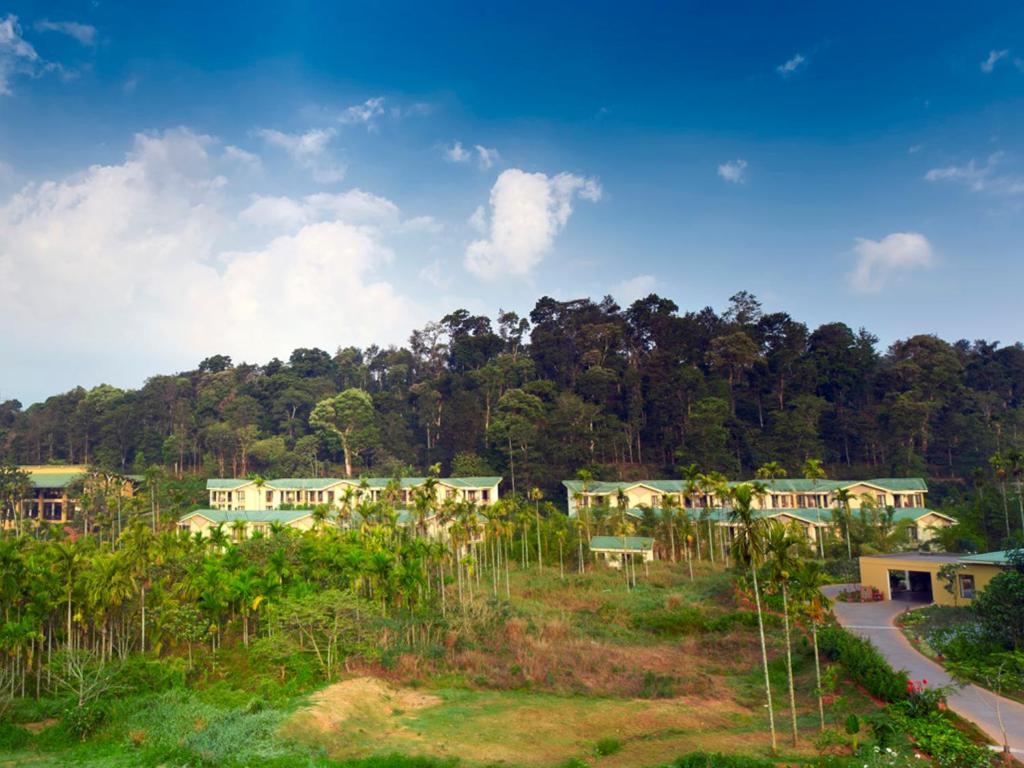 a group of houses in a field with trees at Club Mahindra Virajpet, Coorg in Virajpet