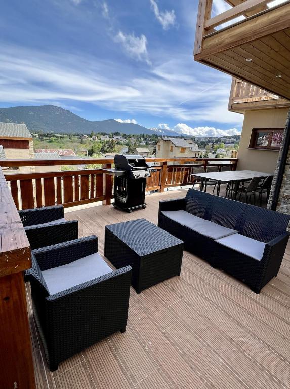 une terrasse avec des canapés et un grill avec des montagnes en arrière-plan dans l'établissement Le chalet des monts, à Formiguères