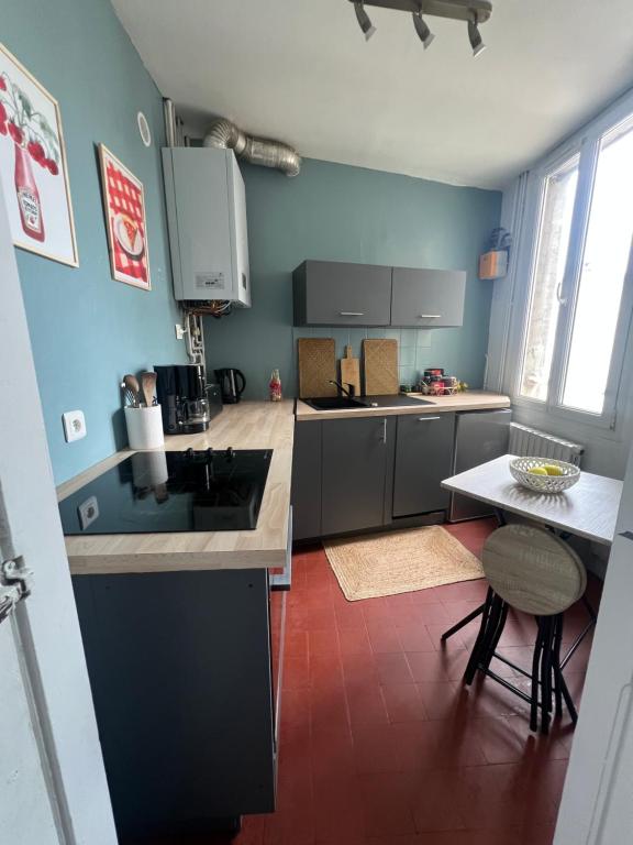 a kitchen with a sink and a table in it at Le cosy Terminus - Le havre - 2 chambres -1 min à pied de la gare in Le Havre
