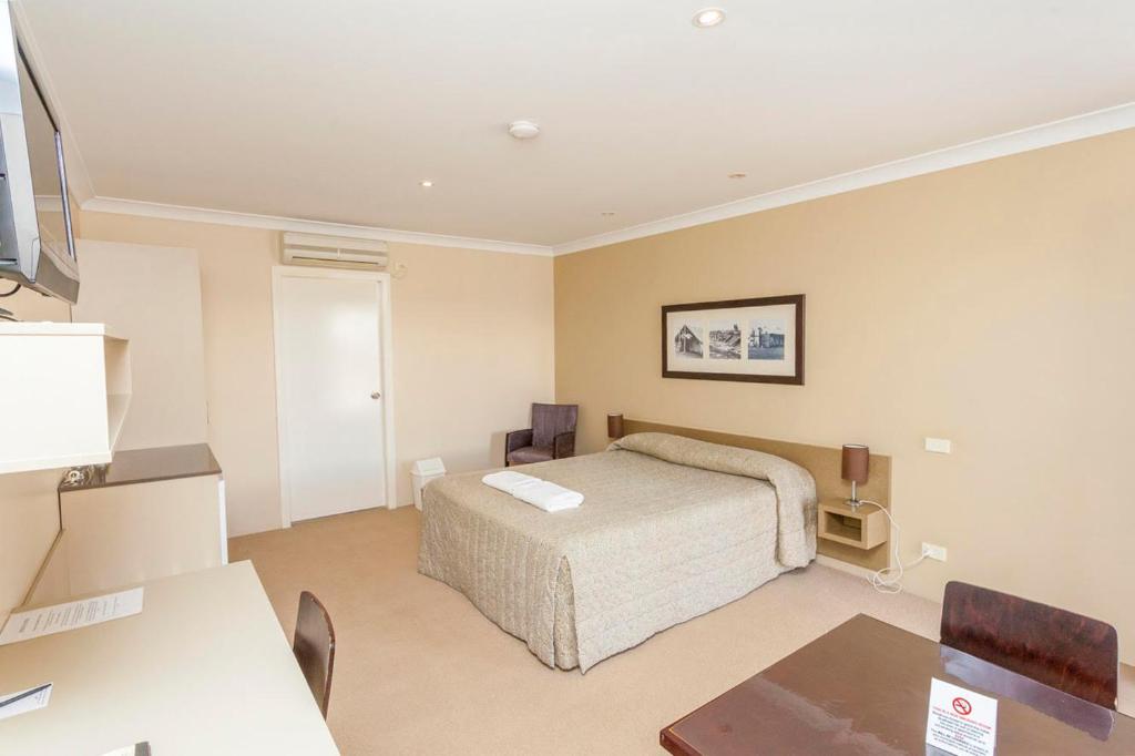 um quarto com uma cama, uma mesa e uma secretária em The Kidman Wayside Inn em Griffith