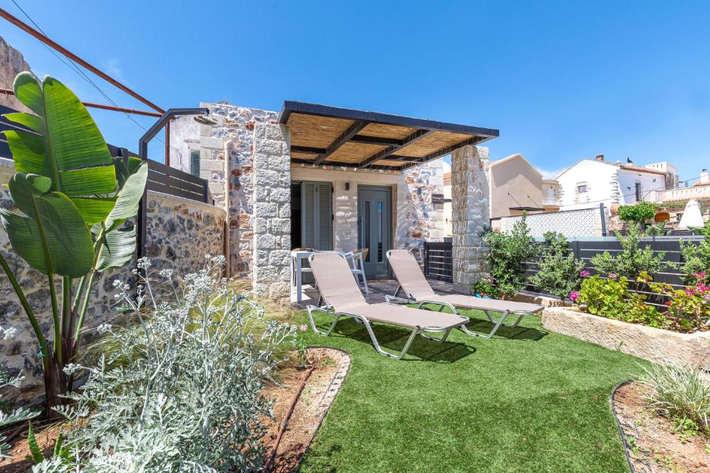 a garden with two chairs and grass at Kefalas Luxury Villas Kelari Accessible Stone Studio in Epáno Kefalás
