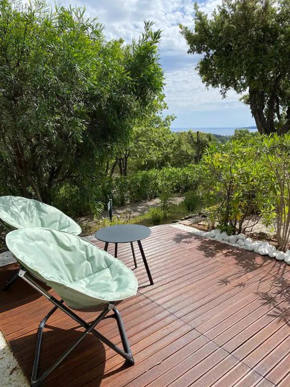 deux chaises et une table sur une terrasse en bois dans l'établissement Appartement T2 dans résidence Les Restanques du Golfe à Grimaud, à Grimaud